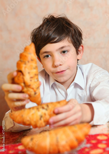 handsome preteen boy play with croissan imagine its a  sheep photo