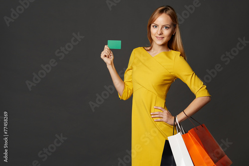 Shopping young woman in the yellow with bags and a credit card o