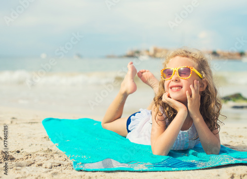 Little girl sunbathing on the beach. Place for text.