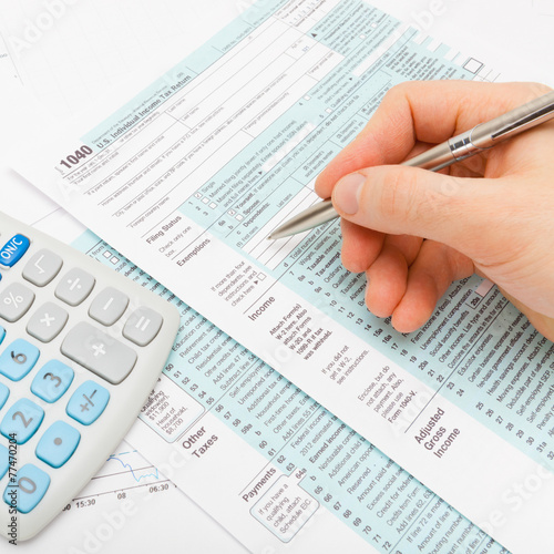 Filling out 1040 US Tax Form - studio shot © niyazz