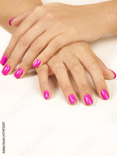 Manos de mujer y uñas pintadas de color rosa sobre fondo blanco