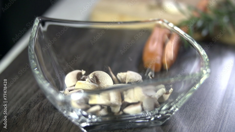 Slices of button mushroom falling into glass dish Slices of button mushroom falling into glass dish