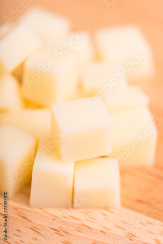 cheese cubes close up on wooden background - selective focus