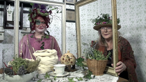 Two ladies with strange hats hold wooden frames in their hands which move up photo