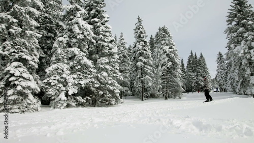 a young man snowboarding and enjoying in the idyllic winter time soroundings photo