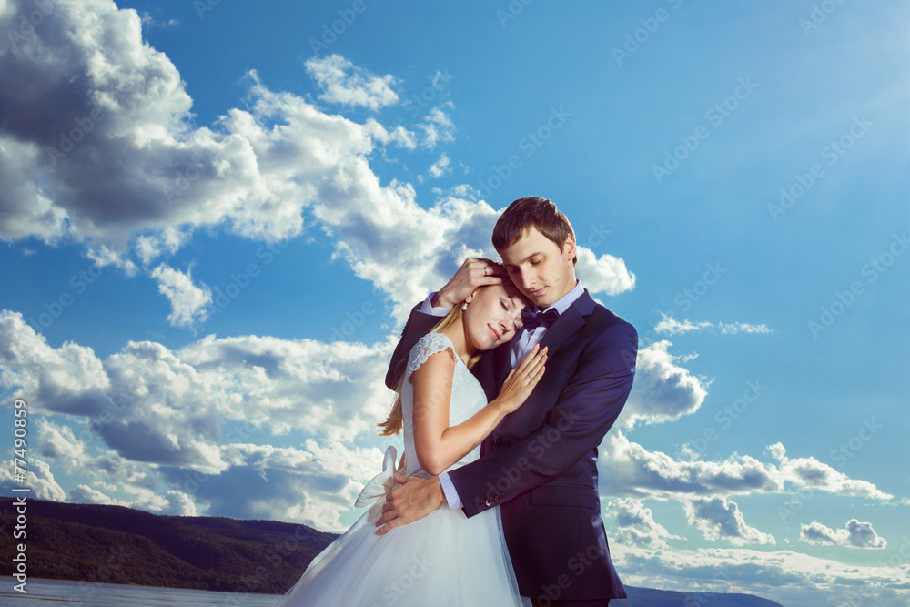 A beautiful young pair is embracing against the sky view.