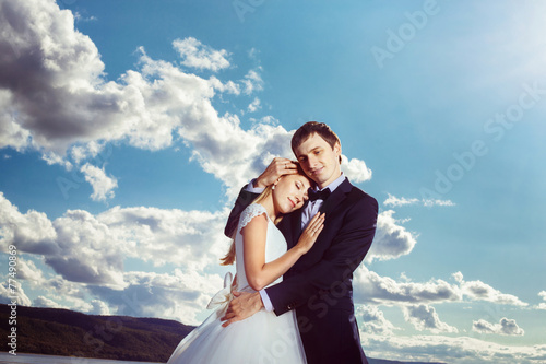 A beautiful young couple is embracing near the river coast. © Mayatnikstudio