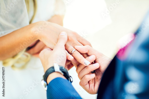 groom placing an engagement ring