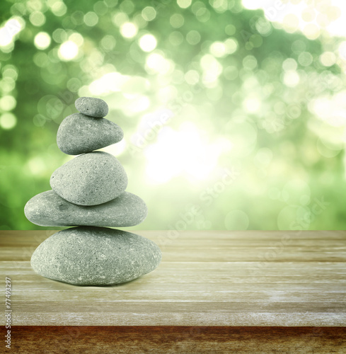 Balancing stones on table in front of green spring background