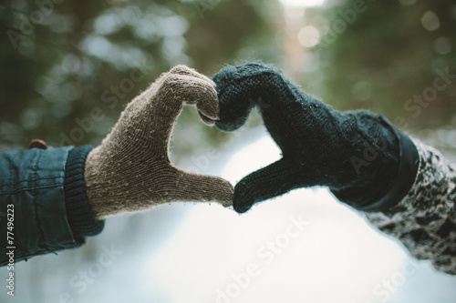 Two hands in gloves holding love heart symbol