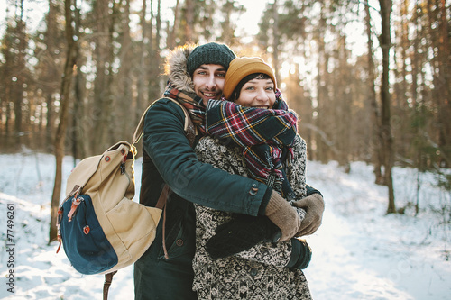 Young man hugs his girlfriend in winter forest