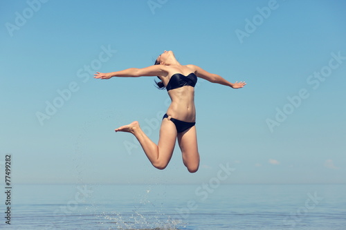 Wallpaper Mural Beautiful young girl jumping on sea Torontodigital.ca