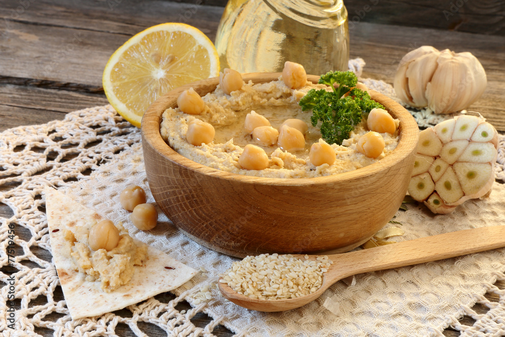 Hummus in a wooden bowl and ingredients to cook it Hummus in a wooden bowl and ingredients to cook it