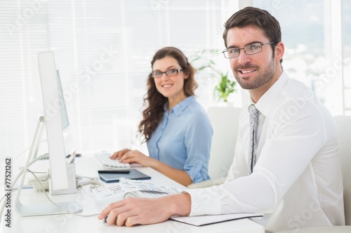 Portrait of smiling team with glasses at desk