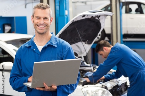 Smiling mechanic using a laptop