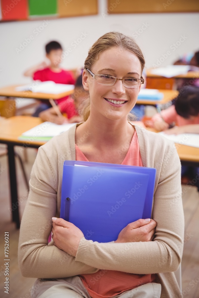 Pretty teacher smiling at camera while holding folder Pretty teacher smiling at camera while holding folder