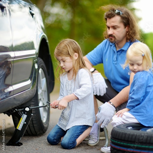 Little girl helping father to change a car wheel