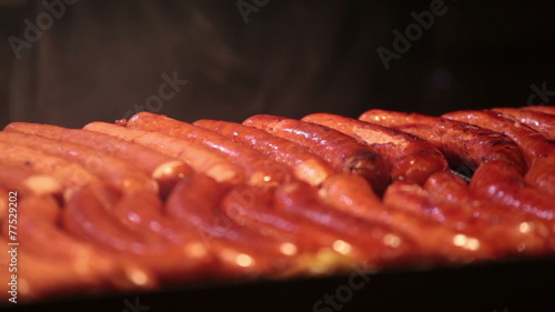 Cook overturns the sausages which are fried on a grill
