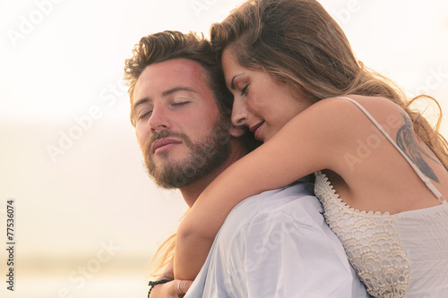 woman embracing her man from behind at sunset