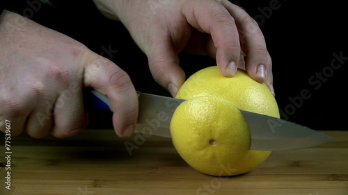 Cutting into grapefruit in slow motion on black background photo