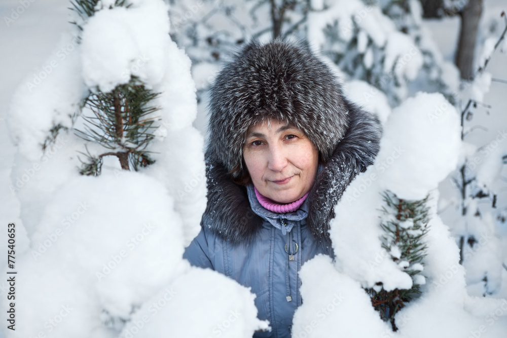 Fototapeta premium Woman face in beauty snowy pine branches at winter season