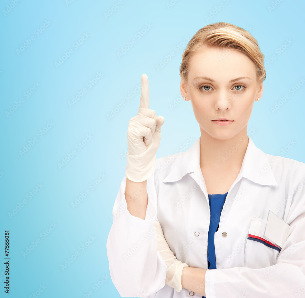 smiling young female doctor pointing her finger up smiling young female doctor pointing her finger up