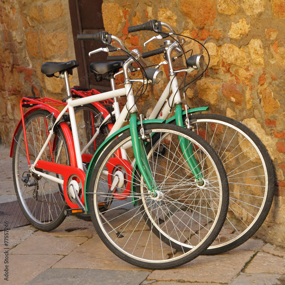 two bicycles painted in colors of Italy  against on stone wall o