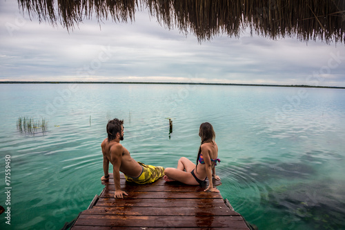 Beautiful couple in love looking at tranquil Bacalar lake.