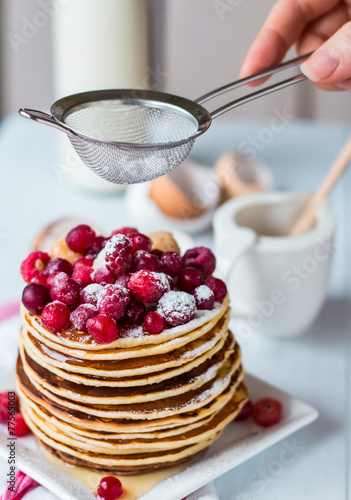 Pancake with cranberries, raspberries and powdered sugar, hands