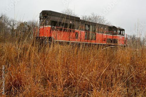 Vintage abandoned train locomotive in a field of wild weeds photo