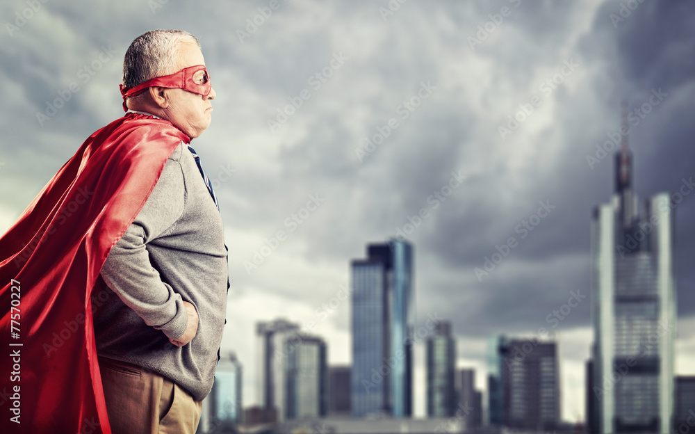 Senior superhero standing in front of a city