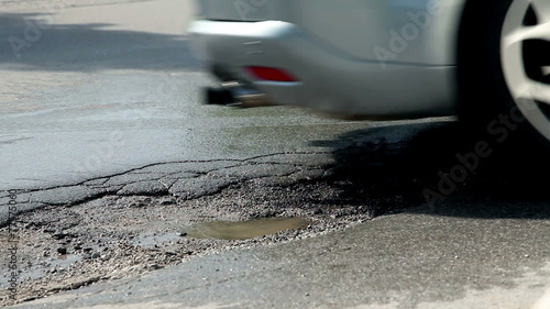 Big hole in asfalt on road and car drives over