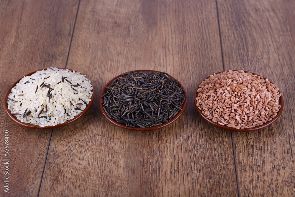 Different kinds of rice on plates on wooden background Different kinds of rice on plates on wooden background