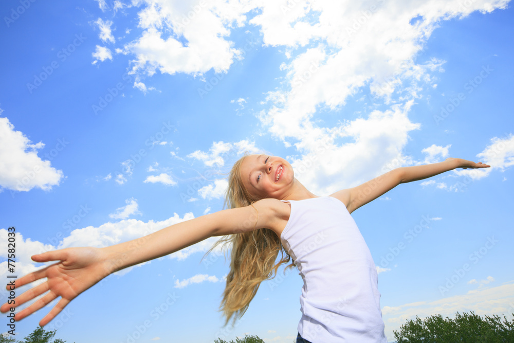 A smiling little girl in white blank t-shirt over blue sky A smiling little girl in white blank t-shirt over blue sky