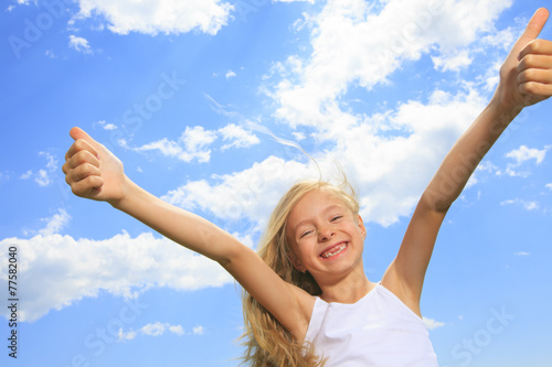 A smiling little girl in white blank t-shirt showing thumbs up