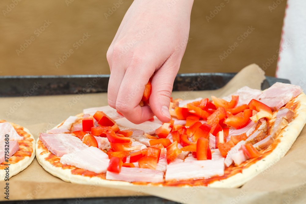 woman puts diced peppers on pizza