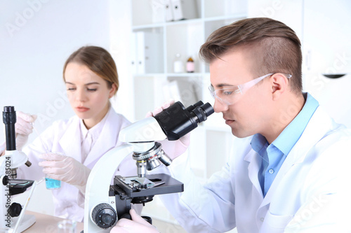 Young female and male scientists with microscope in laboratory