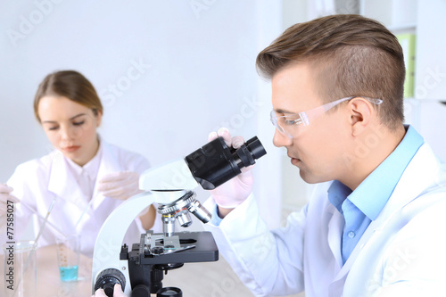 Young female and male scientists with microscope in laboratory