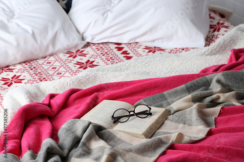Book and glasses on bed close-up