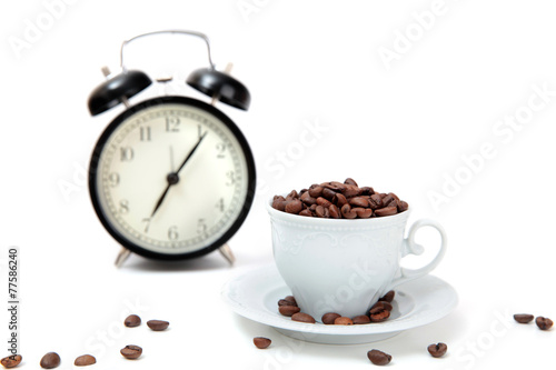 The alarm clock and white cup filled by coffee beans