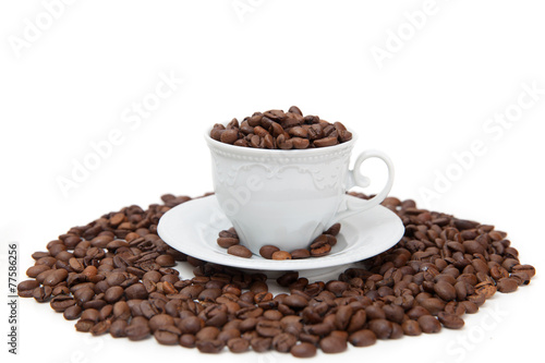 The white mug full of coffee beans isolated on white background