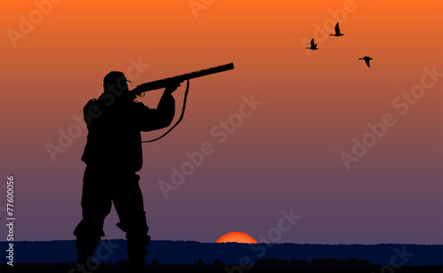 hunter with gun at sunset background