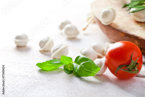 Tortellini and vegetables on white wooden background photo