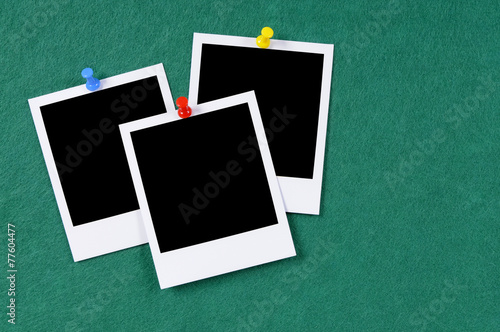 Cluster group of three blank polaroid style photo frame prints with pushpin pinned to a green felt notice or bulletin board
