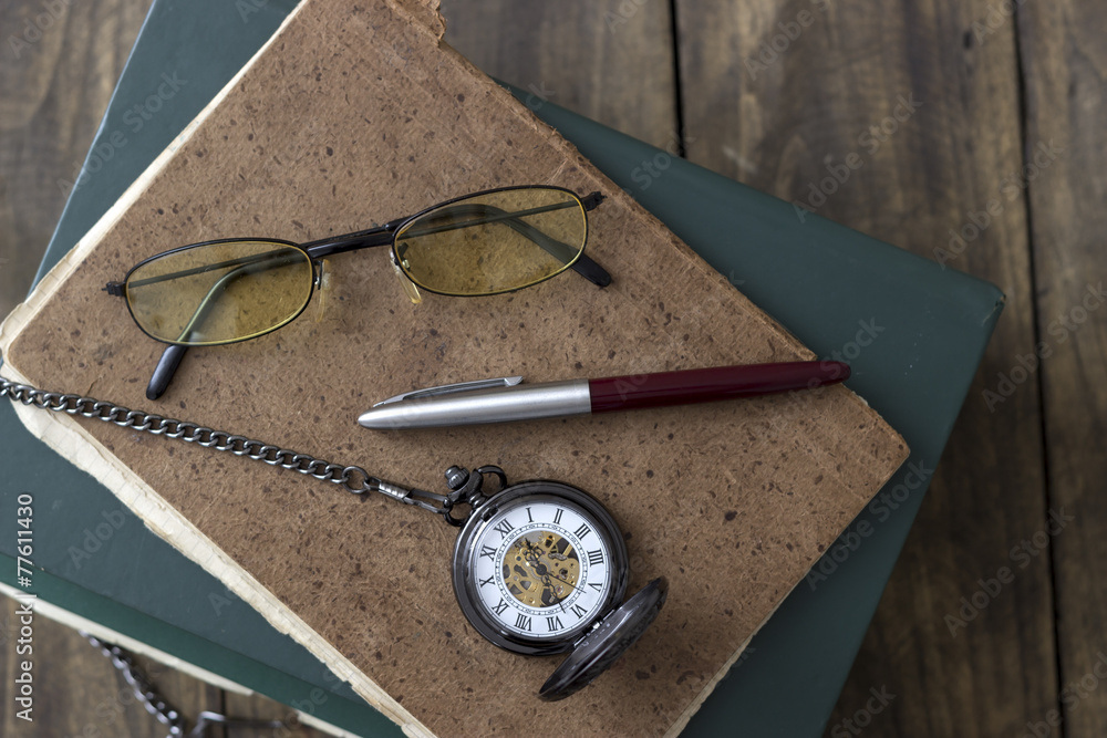 An antique pocket watch, glasses and books An antique pocket watch, glasses and books