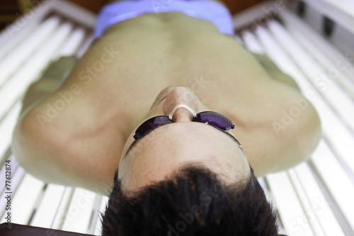 Fotografia A man in a sunbath receiving high degree of ultraviolet light.