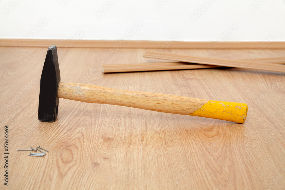 Laminate flooring of room, hammer batten and nails at floor