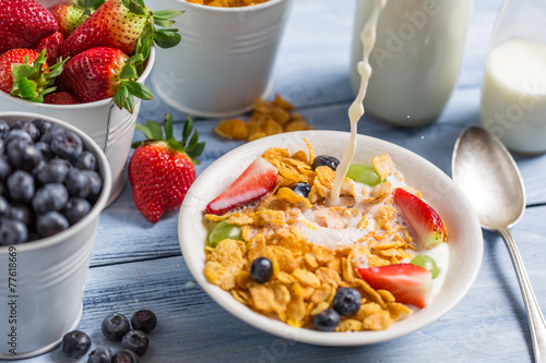 Pouring milk into cornflakes with fruits