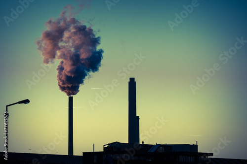 Power plant silhouette at dusk emitting large clouds of smoke photo