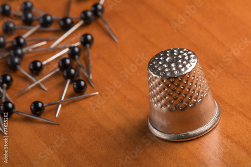Thimble and needles on wooden table